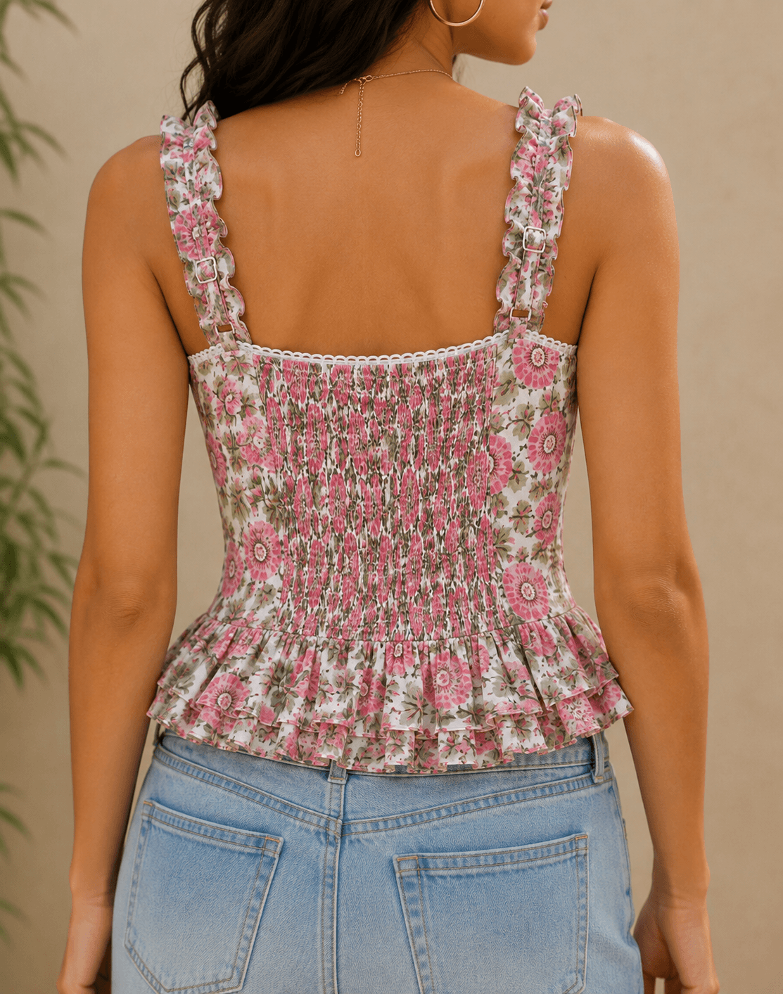 Back view of model wearing women's pink floral peplum crop top with elasticated centre back and adjustable straps.